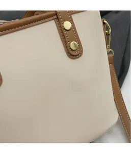 Detail of cream bucket bag with brown leather trim, white stitching and gold hardware