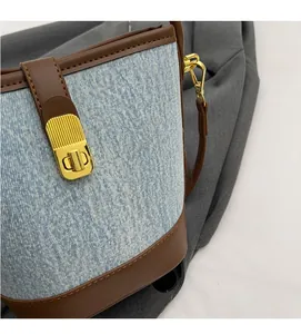 Close-up of blue denim bucket bag with brown leather trim and vintage gold clasp