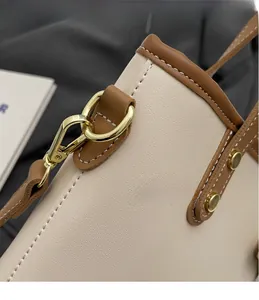 Detail of cream and brown leather bucket bag with contrast stitching and gold metal hooks