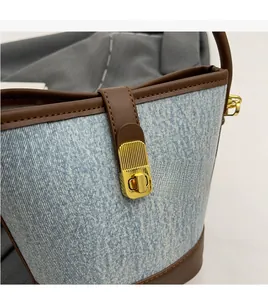 Detail of premium golden twist lock on light blue denim bucket bag with brown trim