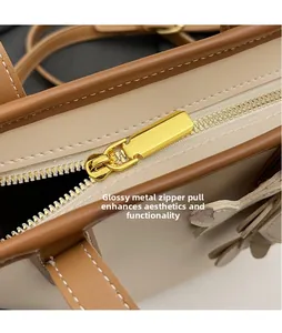 Detail of smooth gold hardware zipper on beige and brown leather bucket bag
