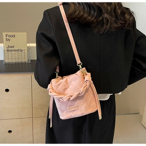Detail der rosa gesteppten Beuteltasche mit Webgriff und Goldbeschlägen an einem Model