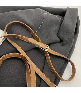 Detail of adjustable brown leather shoulder strap with white contrast stitching and gold buckle