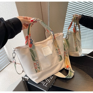 Detail of canvas tote bag with colorful floral embroidery on the wide shoulder strap