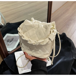 Detail einer cremefarbenen Stepp-Beuteltasche mit Knotengriff und goldener Hardware