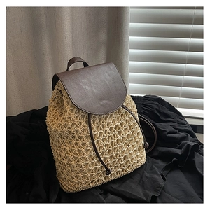 Detailed view of handmade straw woven backpack with hollow patterns and brown leather straps