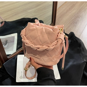 Detail einer rosa gesteppten Beuteltasche mit gewebtem Griff und Mode-Metalllogo