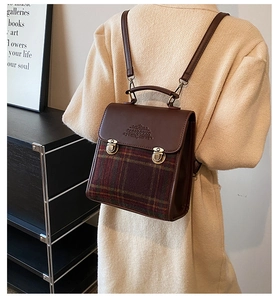 Detailed view of a vintage British style plaid backpack with brown faux leather trim
