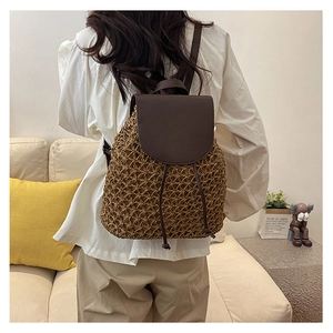 Detail of a straw woven backpack with brown leather flap and drawstring closure for travel