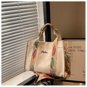 Detailed close-up of cream canvas tote bag with vibrant geometric embroidered wide straps