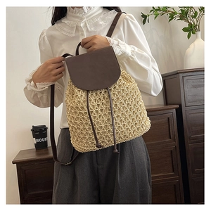 Detail of hand-woven straw backpack with brown leather straps and drawstring closure