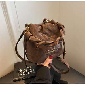 Detailansicht der braunen gesteppten Beuteltasche mit Kordelzug und modischem Logo-Tag