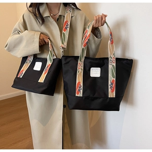 Detailed comparison of large and small black nylon tote bags with floral ribbon straps