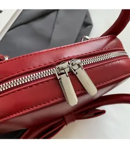 Detail of premium red handbag featuring smooth double silver metal zippers and hardware