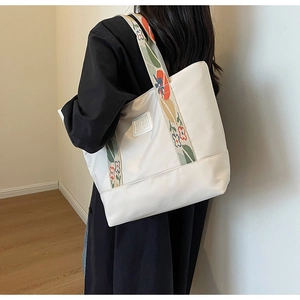 Detail of white canvas tote bag with floral embroidered strap and SIJI CHAO logo patch