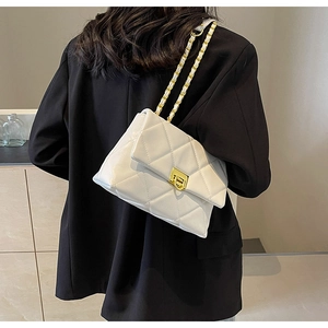 Detailed back view of model wearing white quilted crossbody bag with gold chain strap