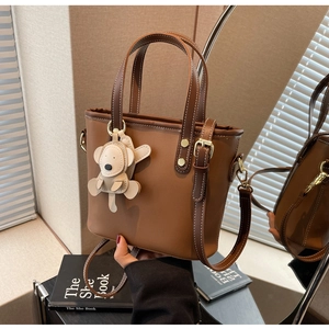 Detail of vintage brown bucket bag featuring contrast stitching and monkey charm