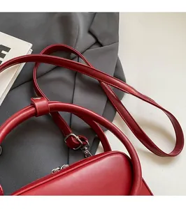 Detail of red leather handbag with adjustable shoulder strap on minimalist grey blazer