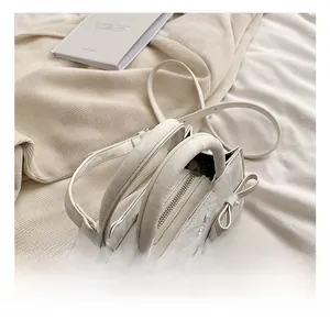 Detail der weißen Handtasche mit Schleifen, Kunstlederstruktur und Schultergurt