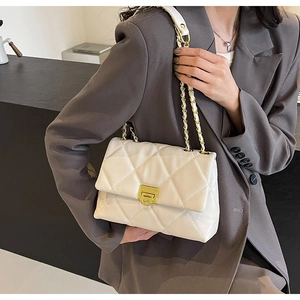 Detailed side view of white quilted crossbody bag with metal chain strap on model