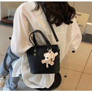 Detail of black bucket bag with white contrast stitching and cute beige animal charm