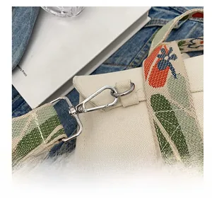 Detail of silver metal hook and colorful jacquard strap on beige canvas tote bag