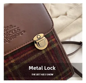 Macro shot of vintage gold metal buckle and textured leather on a plaid shoulder bag