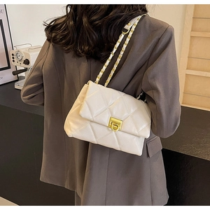 Chic beige quilted shoulder bag with gold chain strap shown on person in brown suit