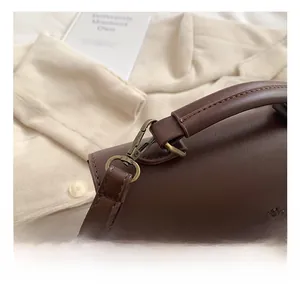 Detailed close-up of dark brown vintage faux leather handbag with bronze swivel hooks