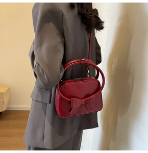 Close-up of red matte leather handbag with bow detail and unique circular handle