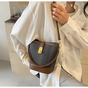 Detail of tweed bucket bag with brown leather trim and golden buckle on model