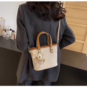 Detailed back view of a beige and brown bucket bag with a cute bear charm accessory