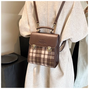 Detail view of retro plaid backpack with leather flap and bronze buckles worn by a model