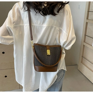Detailed shot of vintage bucket bag featuring grey twill and brown leather stitching