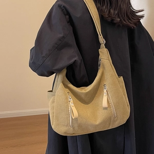 Grand sac fourre-tout en toile kaki avec deux poches zippées porté sur un manteau noir