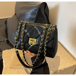Close-up of black quilted leather shoulder bag with gold chain strap and turn-lock closure