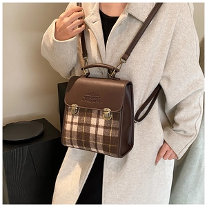 Close-up of retro plaid patchwork backpack with vintage metal buckles and leather handle