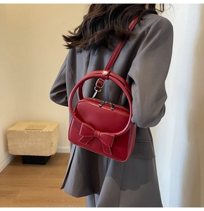 Red bow handbag shown on model to demonstrate size and stylish crossbody fit