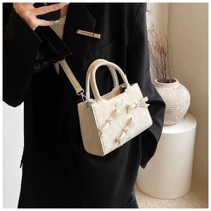 Detail der cremeweißen Handtasche mit 3D-Schleifen, Silberlogo und Marmortextur