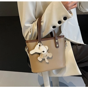 Detail of camel bucket bag with brown contrast trim and cute bear letter charms
