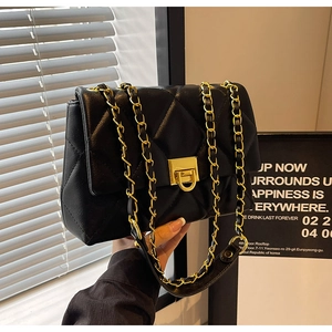 Detail of black quilted leather shoulder bag with gold chain strap and turn-lock closure