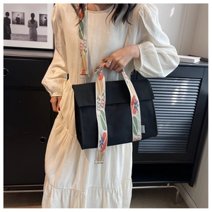 Detail of black canvas tote bag featuring a colorful floral patterned wide shoulder strap