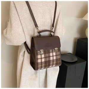 Detail of vintage plaid and leather backpack showing the metal buckles and handle