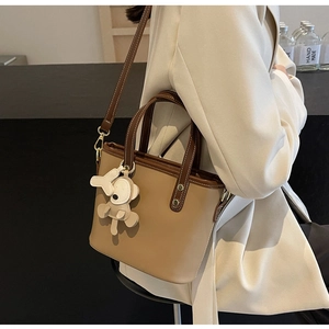 Detail view of khaki bucket bag with adjustable shoulder strap and animal charm
