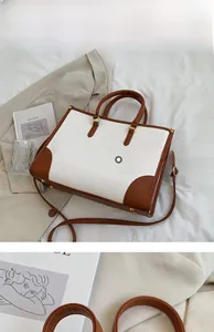 Detail of white crocodile pattern tote with gold metal buckles and brown accents