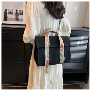 Detail of black canvas tote bag featuring floral wide strap on model back view