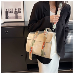 Close-up of white canvas shoulder bag featuring a colorful floral jacquard wide strap