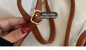 Close-up of adjustable caramel brown leather shoulder strap with golden metal buckle