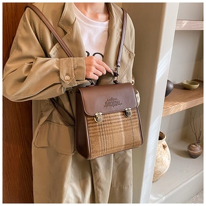 Detail of vintage brown plaid backpack with metal clasp and leather flap shown on model