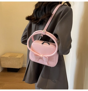 Chic pink handbag with large bow detail and round metal handle shown on model